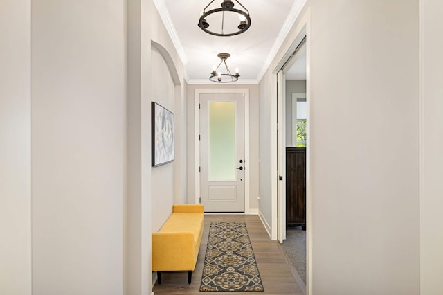 doorway with ornamental molding, dark wood-type flooring, and an inviting chandelier