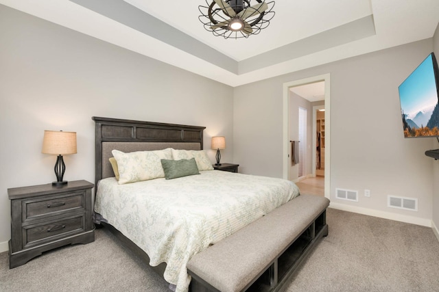 bedroom with a raised ceiling and light carpet