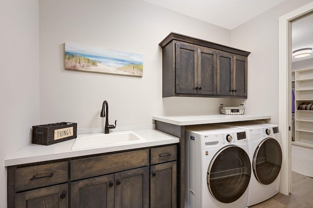 laundry room with separate washer and dryer, sink, cabinets, and light wood-type flooring