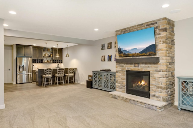 carpeted living room with bar and a stone fireplace