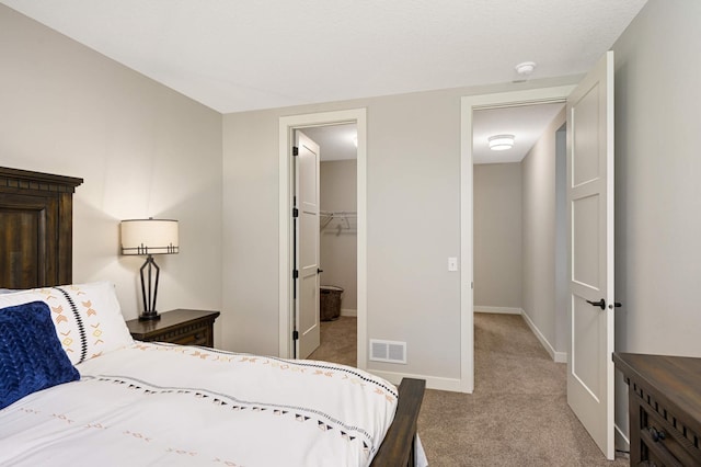 bedroom featuring light colored carpet and a walk in closet