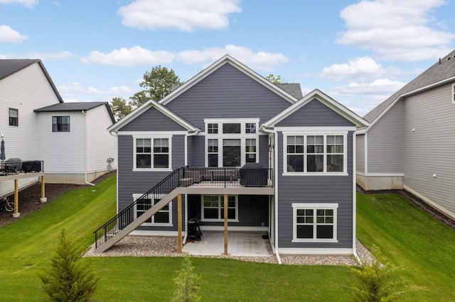 rear view of property featuring a wooden deck, a yard, and a patio area