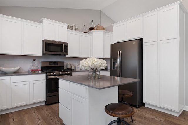 kitchen with stainless steel appliances, lofted ceiling, a center island, and white cabinets