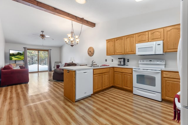 kitchen featuring light countertops, open floor plan, a sink, white appliances, and a peninsula