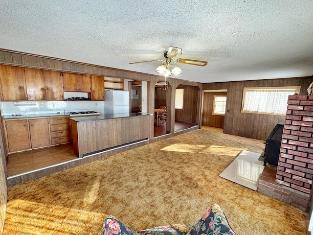 kitchen with a wood stove, white refrigerator, ceiling fan, light carpet, and a textured ceiling