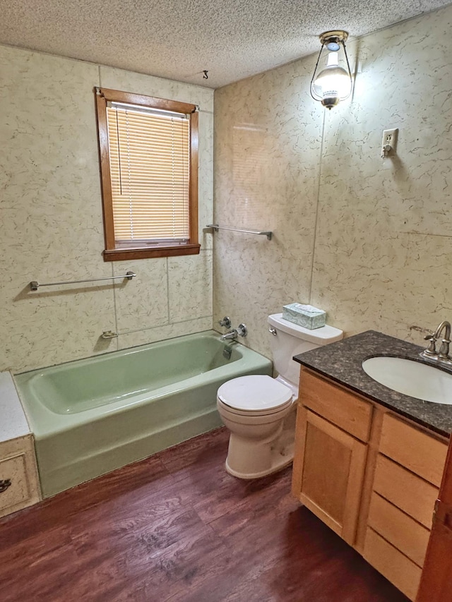 full bathroom featuring hardwood / wood-style flooring,  shower combination, vanity, a textured ceiling, and toilet