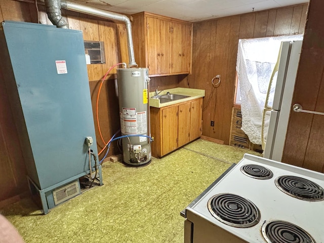 kitchen featuring white appliances, sink, water heater, and wood walls