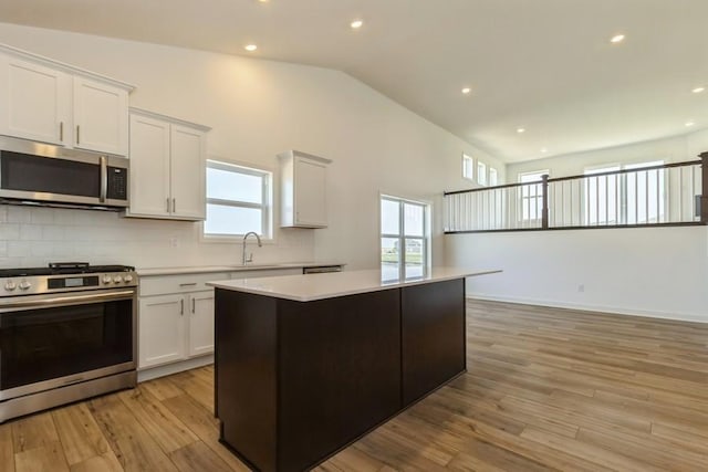 kitchen featuring stainless steel appliances, a center island, white cabinets, and light wood-type flooring