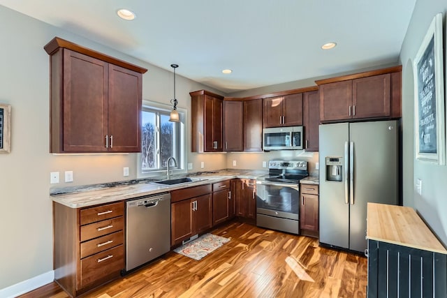 kitchen featuring butcher block counters, sink, hanging light fixtures, appliances with stainless steel finishes, and hardwood / wood-style flooring