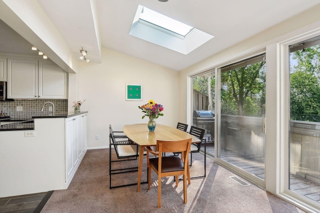 dining space featuring lofted ceiling with skylight and carpet