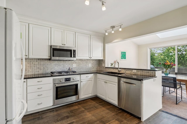 kitchen featuring sink, appliances with stainless steel finishes, white cabinetry, tasteful backsplash, and kitchen peninsula