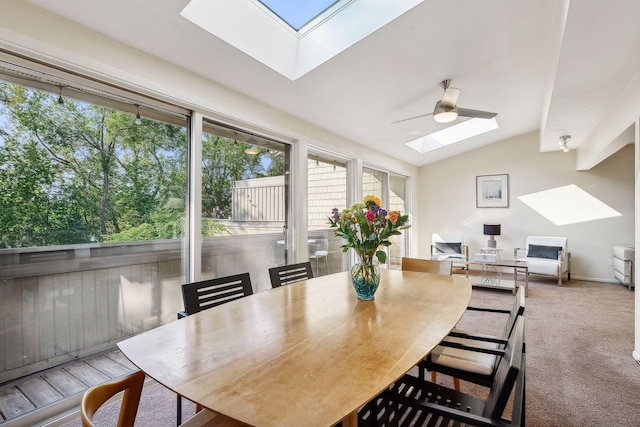 dining space featuring ceiling fan, vaulted ceiling with skylight, and carpet