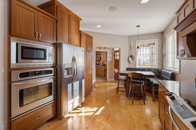 kitchen featuring brown cabinetry, stainless steel appliances, decorative light fixtures, recessed lighting, and light wood-type flooring