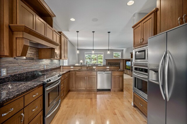 17365 Hanson Ct, Eden Prairie, MN 55347 - kitchen featuring appliances with stainless steel finishes, a sink, brown cabinetry, a peninsula, and decorative light fixtures