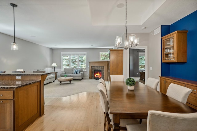 17365 Hanson Ct, Eden Prairie, MN 55347 - dining space with light wood-style floors, a fireplace, and a chandelier