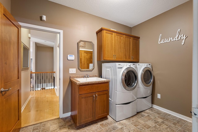 17365 Hanson Ct, Eden Prairie, MN 55347 - laundry room featuring washing machine and dryer, baseboards, cabinet space, stone finish flooring, and a textured ceiling