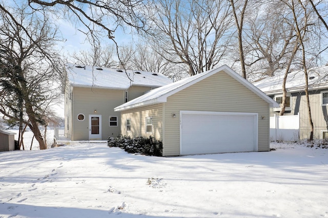 view of snowy exterior with an outbuilding and a garage