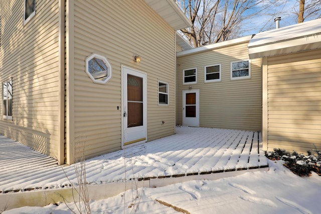 snow covered property entrance featuring a wooden deck