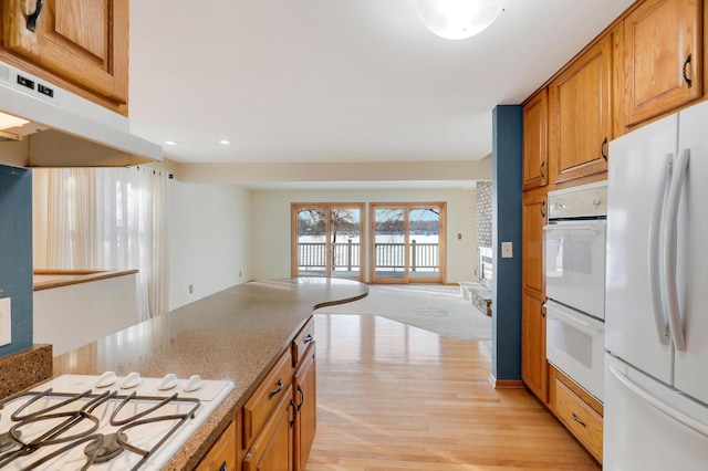 kitchen featuring light stone counters, white appliances, and light hardwood / wood-style floors