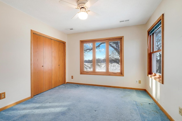 unfurnished bedroom featuring ceiling fan, a closet, and light carpet