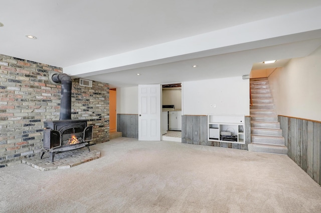 carpeted living room with a wood stove and wood walls