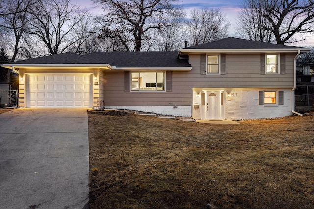 tri-level home with concrete driveway, brick siding, a garage, and a shingled roof