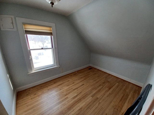 additional living space with vaulted ceiling and light hardwood / wood-style flooring