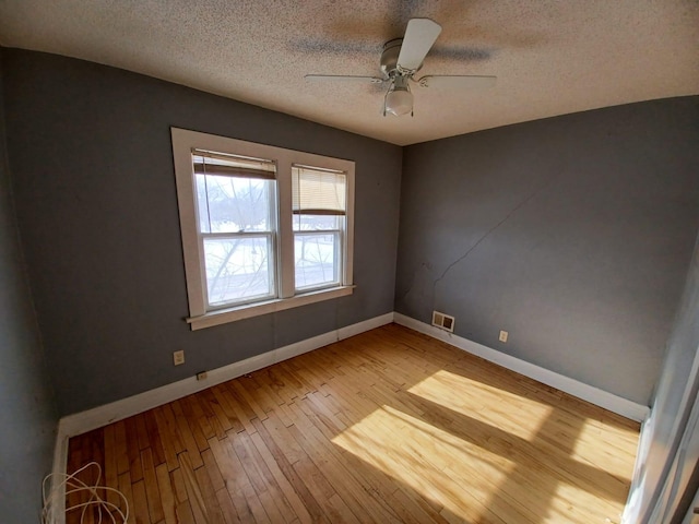 spare room featuring ceiling fan, light hardwood / wood-style floors, and a textured ceiling