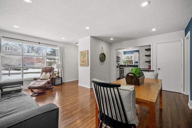 living area featuring a textured ceiling, baseboards, wood finished floors, and recessed lighting