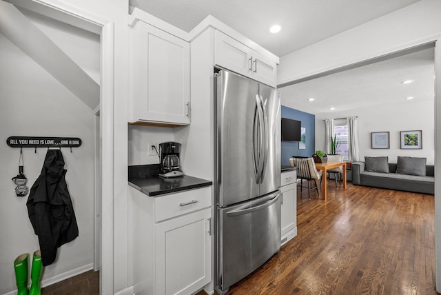 kitchen featuring dark countertops, dark wood-type flooring, freestanding refrigerator, open floor plan, and white cabinets