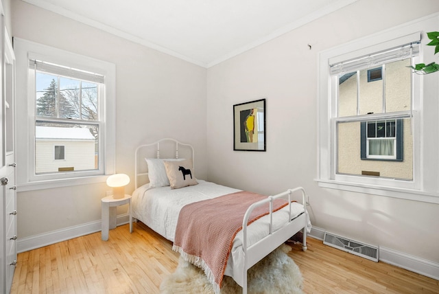 bedroom with crown molding and light hardwood / wood-style floors