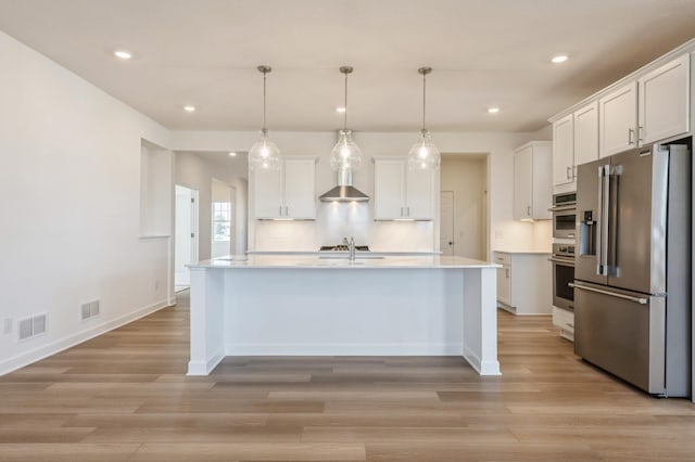 kitchen featuring pendant lighting, stainless steel appliances, an island with sink, and white cabinets