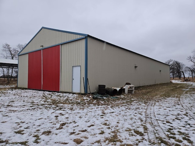 snow covered structure with an outbuilding and a pole building