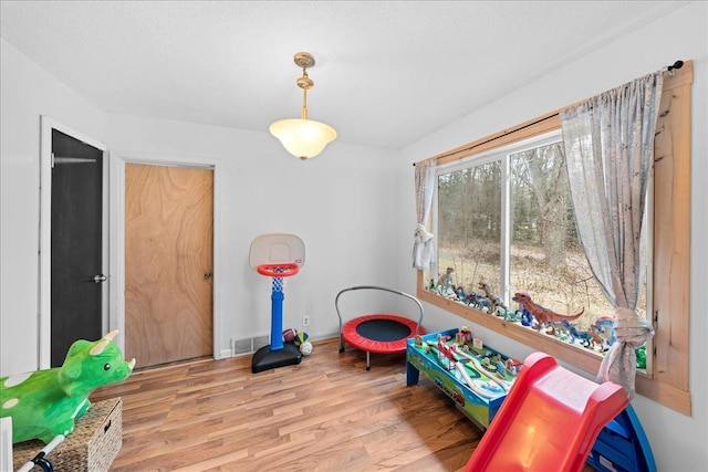 recreation room featuring a textured ceiling and light hardwood / wood-style flooring