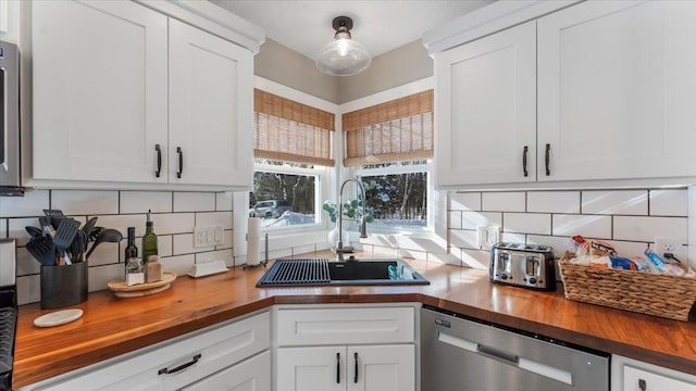 kitchen featuring sink, stainless steel dishwasher, wooden counters, and white cabinets