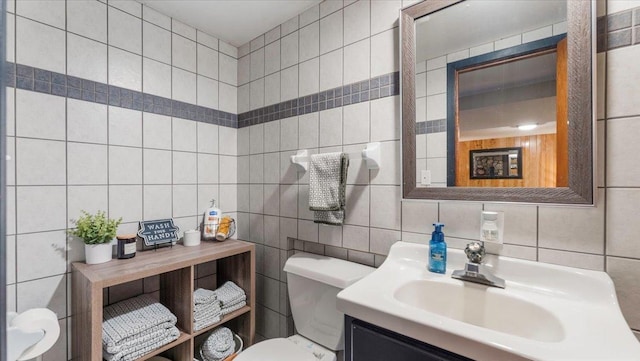 bathroom featuring vanity, tile walls, backsplash, and toilet