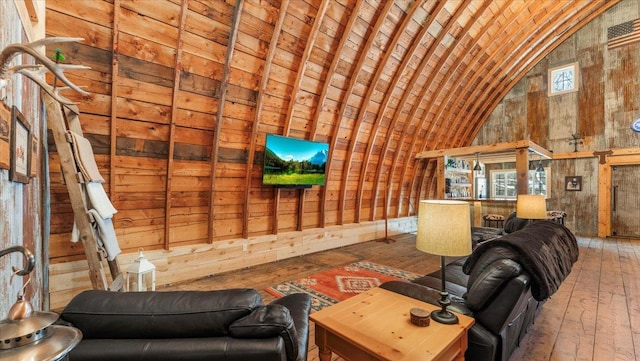 unfurnished living room with wood-type flooring, vaulted ceiling, and wood walls