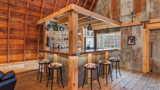 bar with hardwood / wood-style flooring, stainless steel fridge with ice dispenser, and wood walls