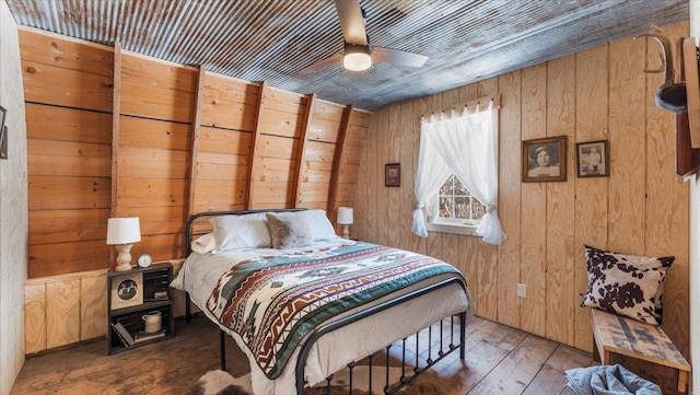 bedroom featuring ceiling fan, wooden walls, and dark hardwood / wood-style flooring