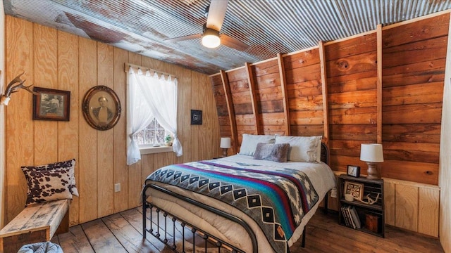 bedroom with ceiling fan, hardwood / wood-style floors, wooden ceiling, and wooden walls