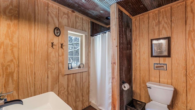 bathroom featuring wooden ceiling, toilet, and wood walls