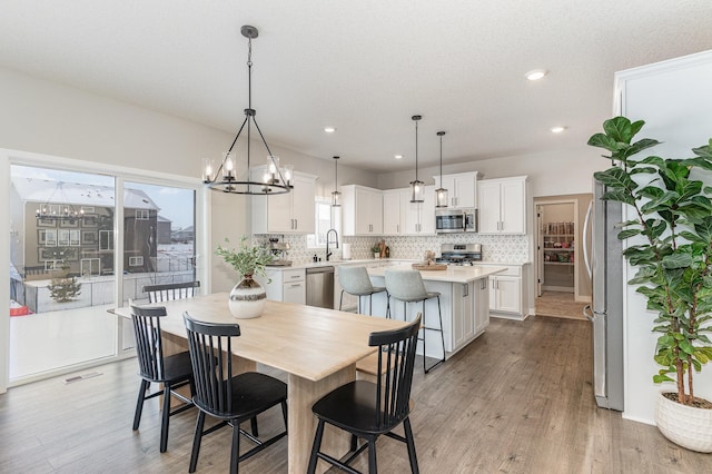 dining space with sink, a notable chandelier, and light wood-type flooring