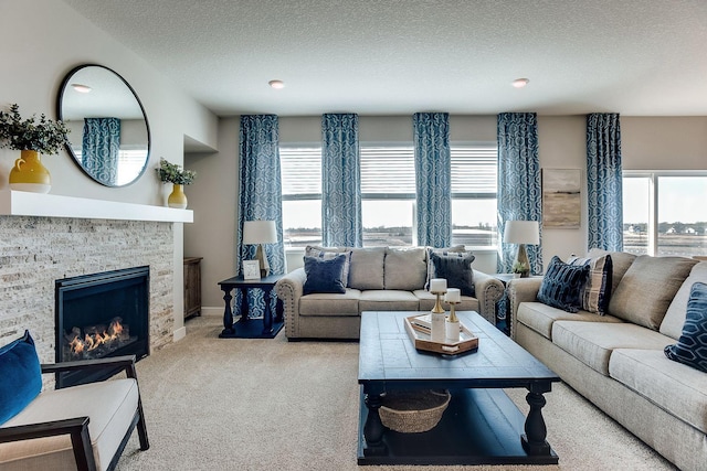 carpeted living room featuring a stone fireplace and a textured ceiling