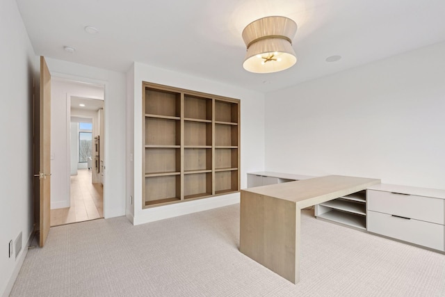 unfurnished office with baseboards, visible vents, and light colored carpet