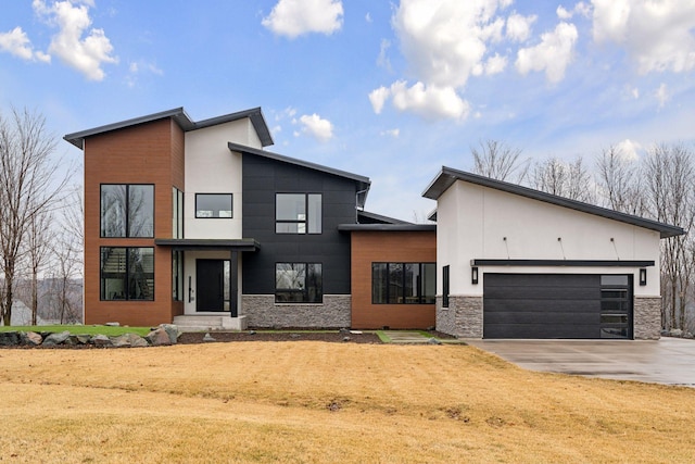 contemporary home with an attached garage, stone siding, and concrete driveway