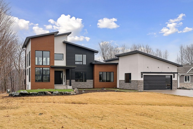 modern home featuring stone siding, driveway, and an attached garage