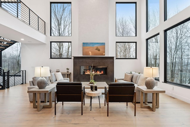 living area featuring a high ceiling, baseboards, wood finished floors, and a high end fireplace