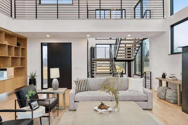 living room with a healthy amount of sunlight, a high ceiling, stairway, and wood finished floors