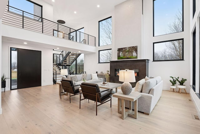 living room featuring stairs, wood finished floors, a glass covered fireplace, and baseboards