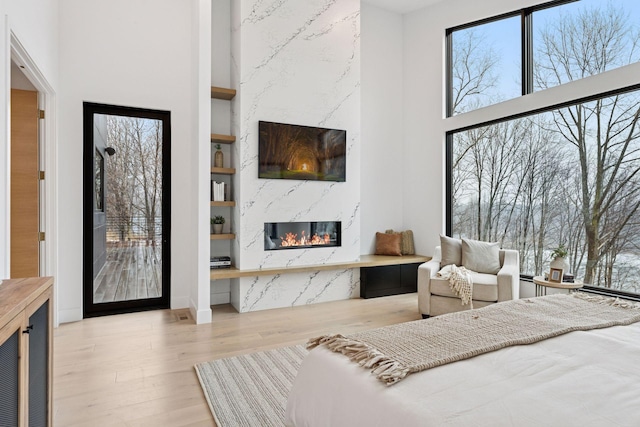 bedroom with a towering ceiling, wood finished floors, and a high end fireplace